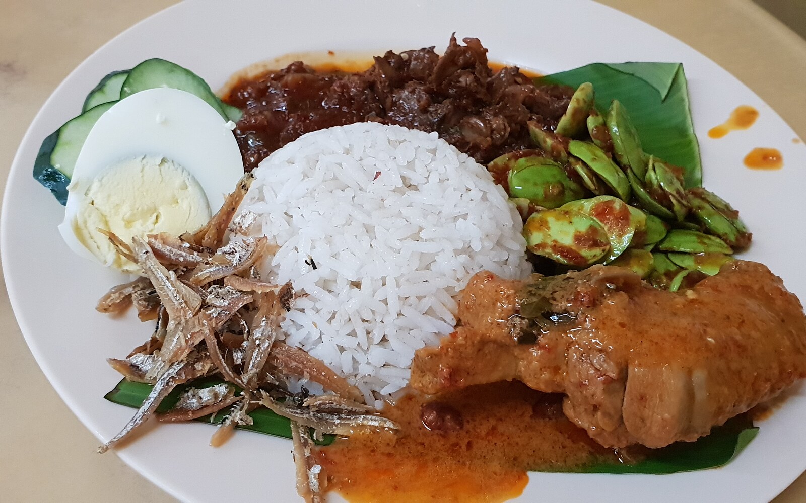 ココナッツご飯、サンバル、小魚、卵、鶏カレー、いか、プタイを一皿にしたマレーシアのナシレマ