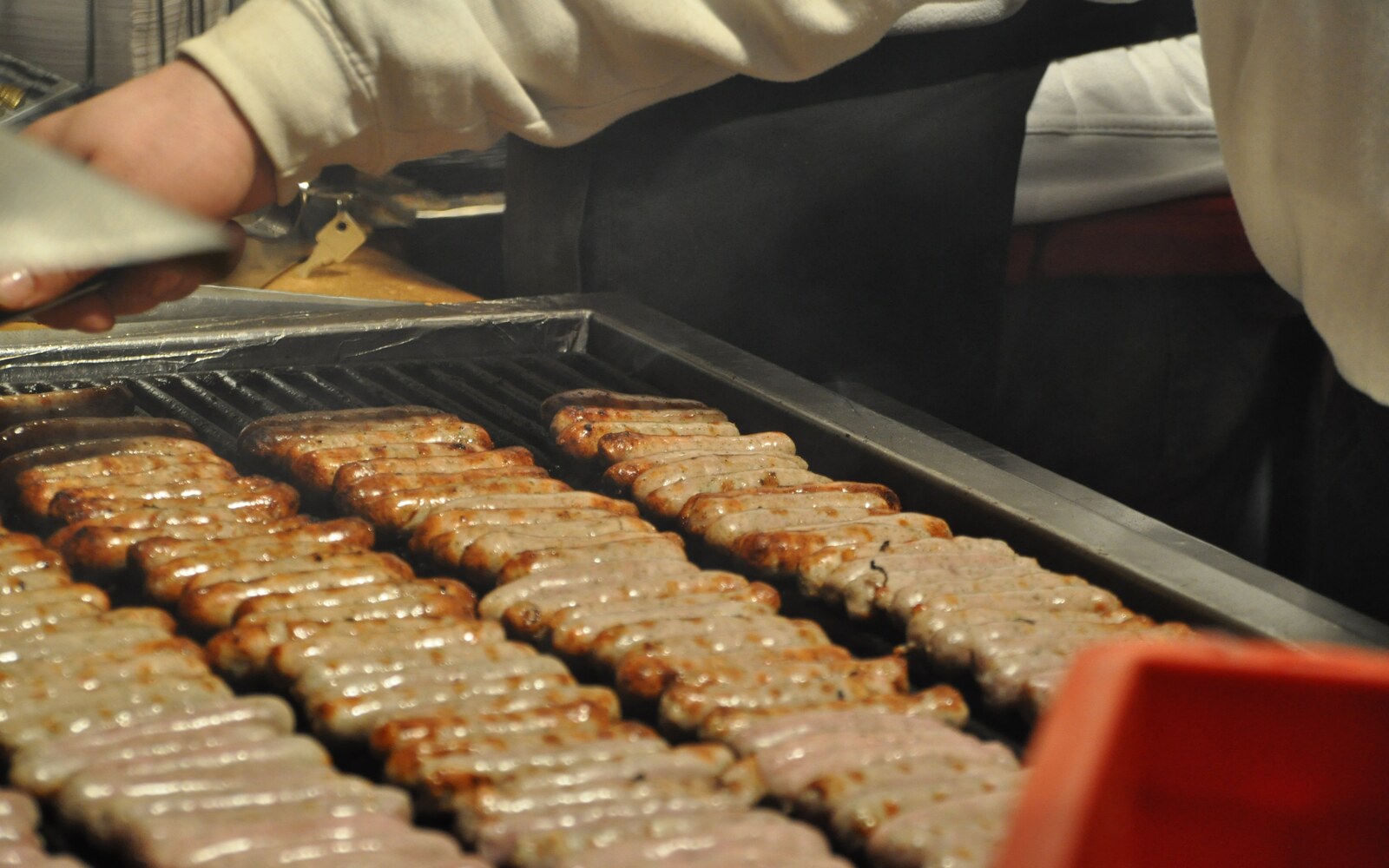 ニュルンベルクのクリスマスマーケットで小ぶりの焼きソーセージを鉄板で焼く場面