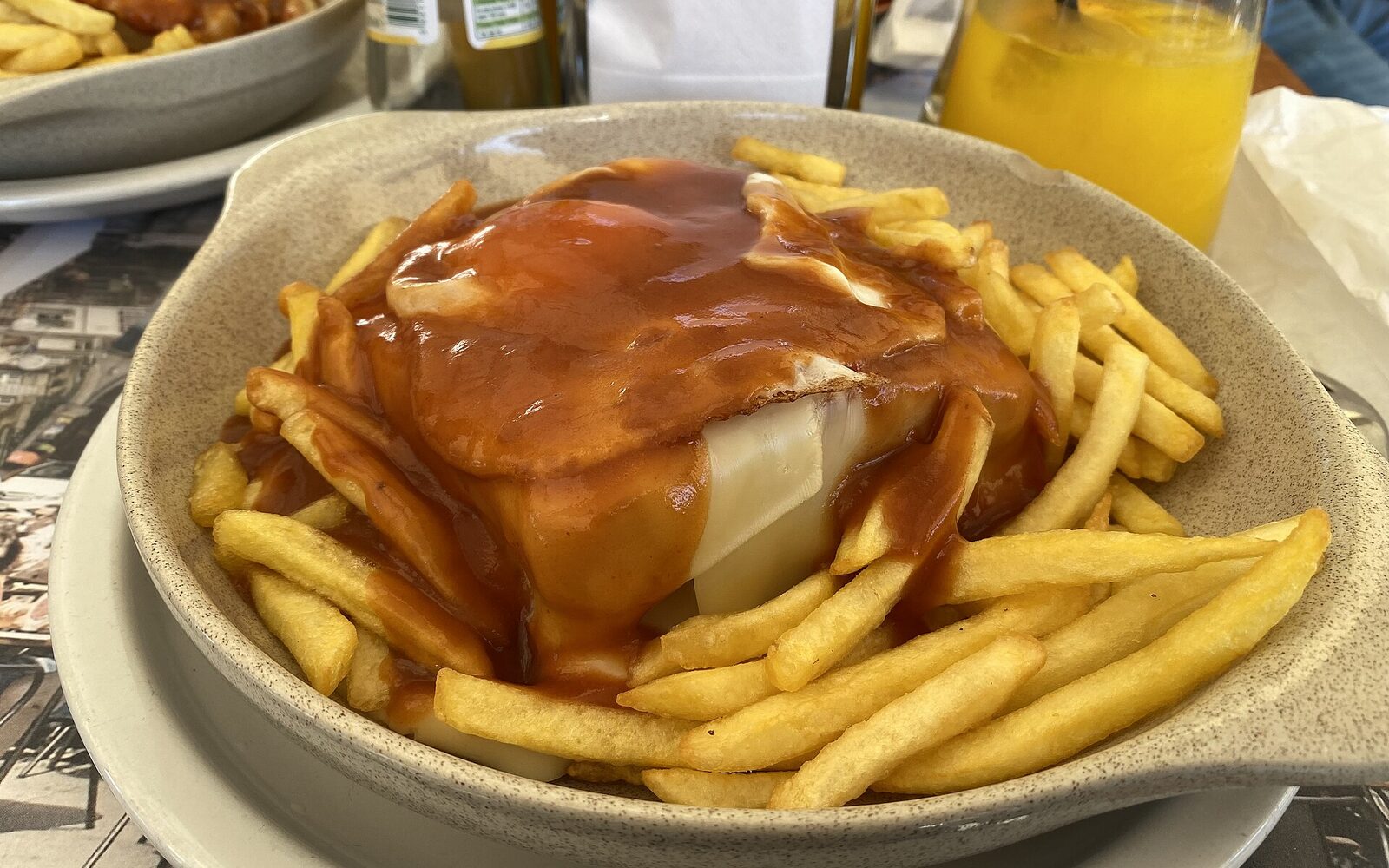 ポルトのリベイラ地区のカフェで供されたチーズとソースを重ねたフランセジーニャとフライドポテト