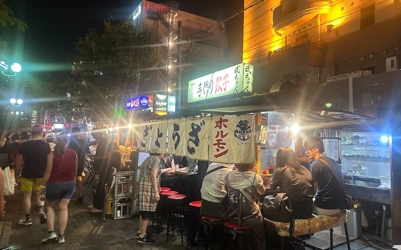 中洲・清流公園で暖簾の前に客が並ぶ夜の屋台（2024年9月撮影）。現在の営業・空席を示しません
