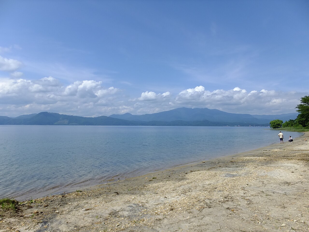 田沢湖の湖岸と秋田駒ヶ岳(2017年7月撮影)。湖面と山の見え方は訪問日と異なります